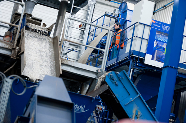 Opérateur de maintenance sur la passerelle d’accès d’une machine de recyclage