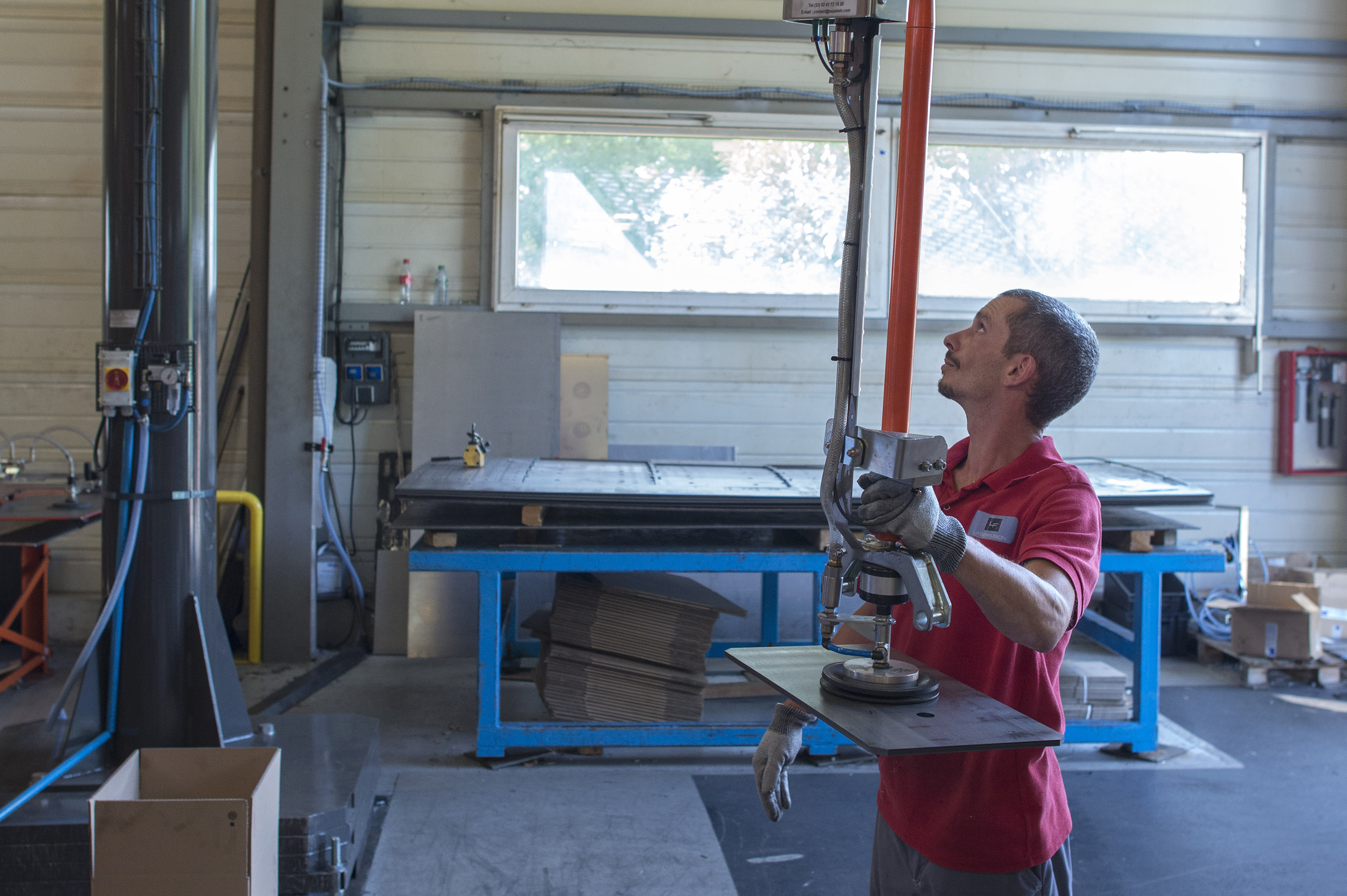 Un opérateur utilise un robot collaboratif pour déplacer une plaque de métal.